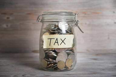 Coins in glass money jar with tax label, financial concept. Vint
